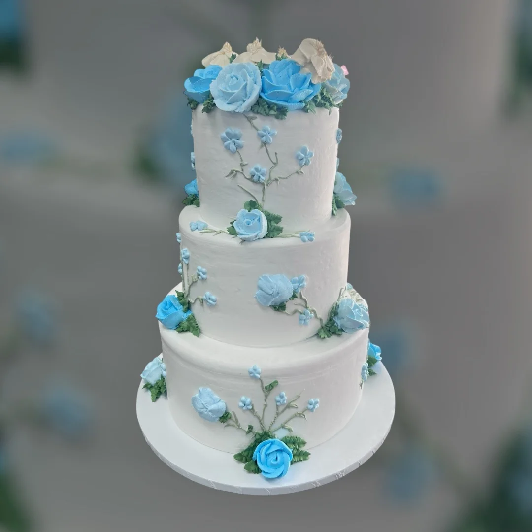 Elegant three-tiered wedding cake with blue roses and floral decorations