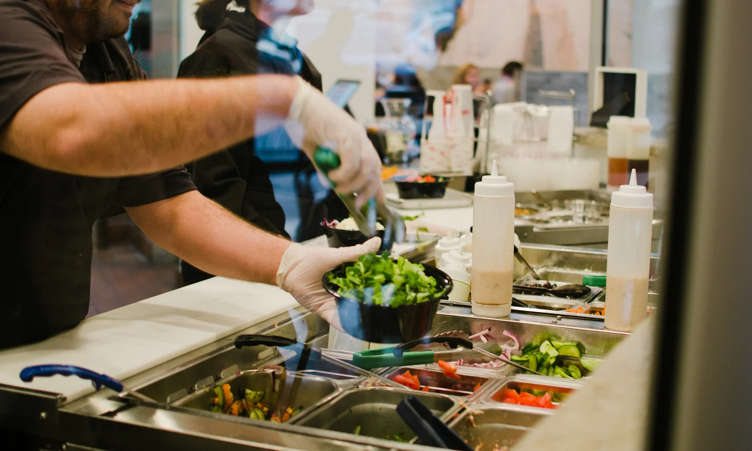 Santorini's team member preparing fresh Mediterranean ingredients behind the counter