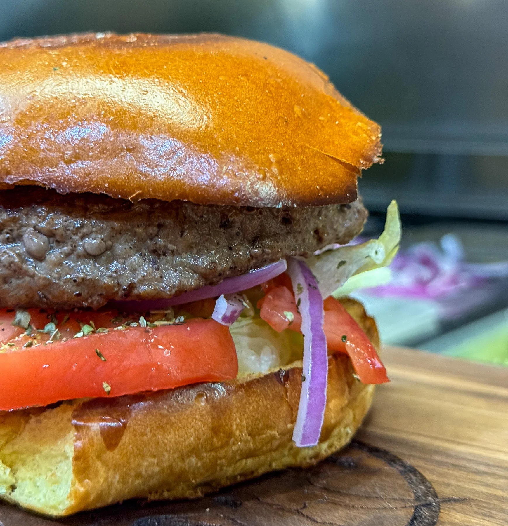  Lettuce, Tomato, Onion – Close-up of burger with grilled beef patty, lettuce, tomato, red onion, and toasted bun.