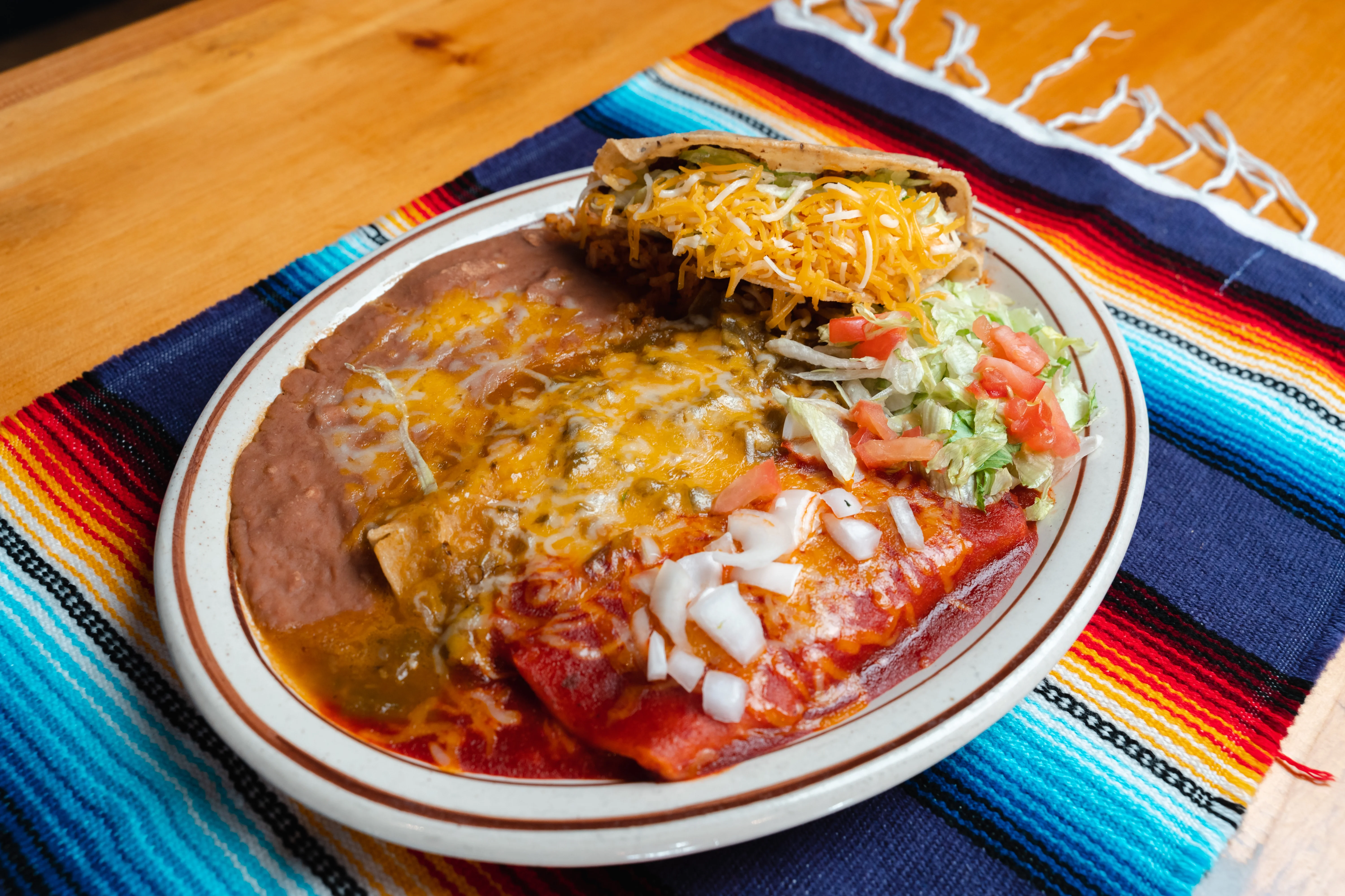 Plate of enchiladas with beans and salad, showcasing Mexican cuisine