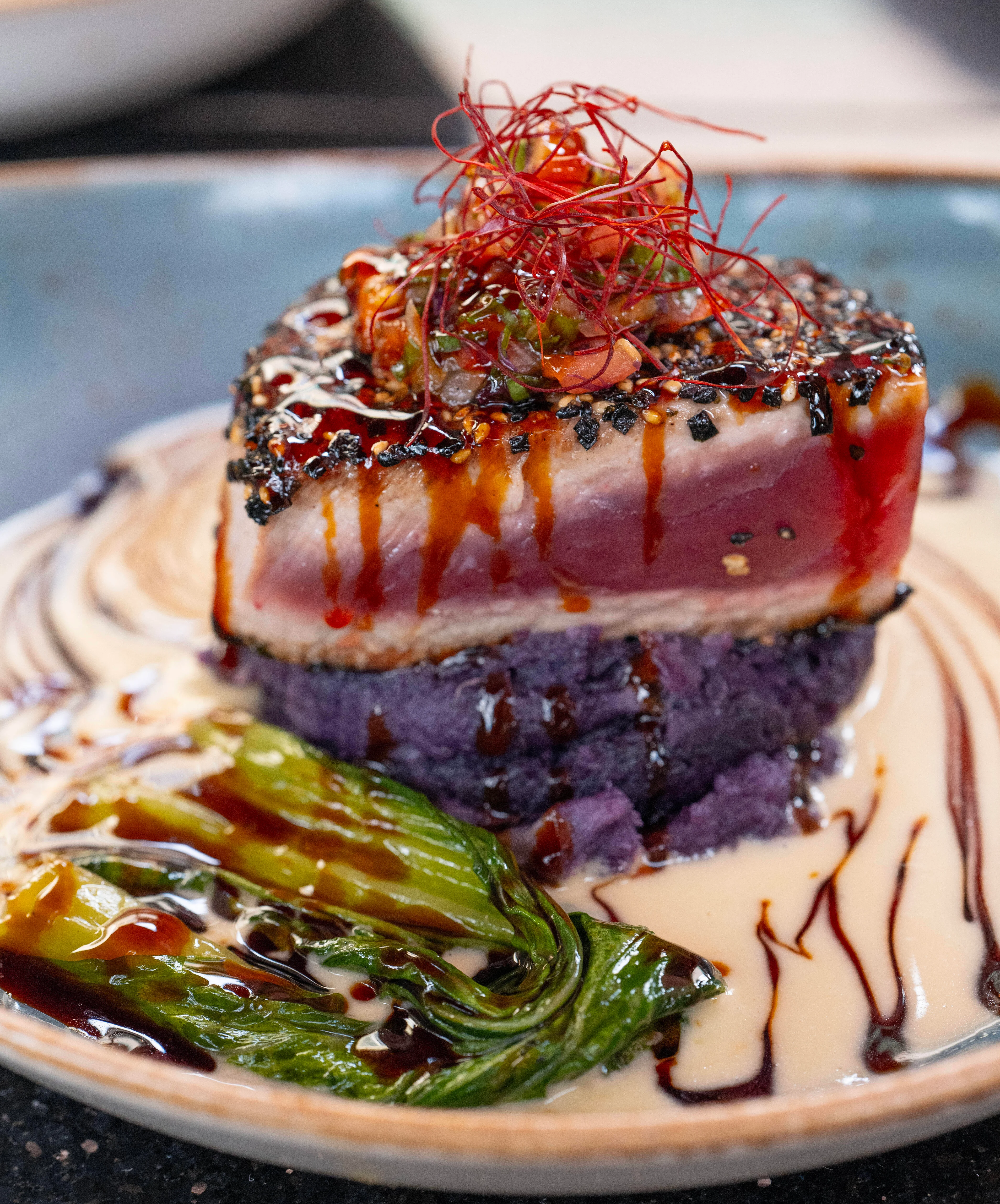 Seared tuna steak with purple potato puree, Asian greens, and sauce