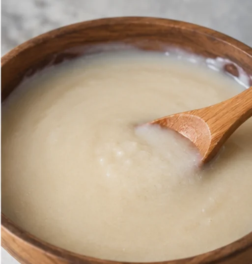 Creamy mixture in a wooden bowl with a wooden spoon.