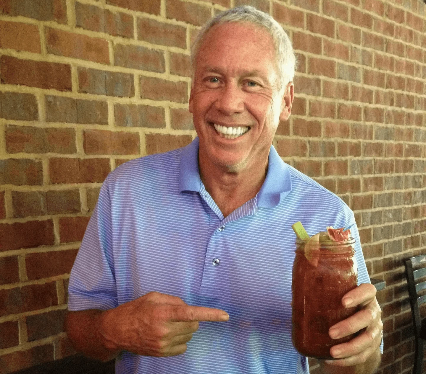 Man enjoying a classic Bloody Mary cocktail in a rustic setting