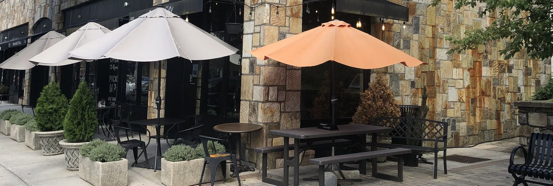 Outdoor dining area with umbrellas and stone wall