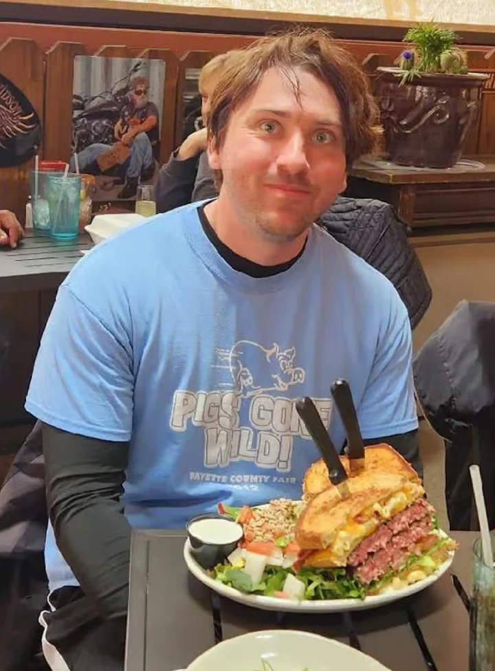 Massive stacked burger with toppings in a rustic restaurant setting