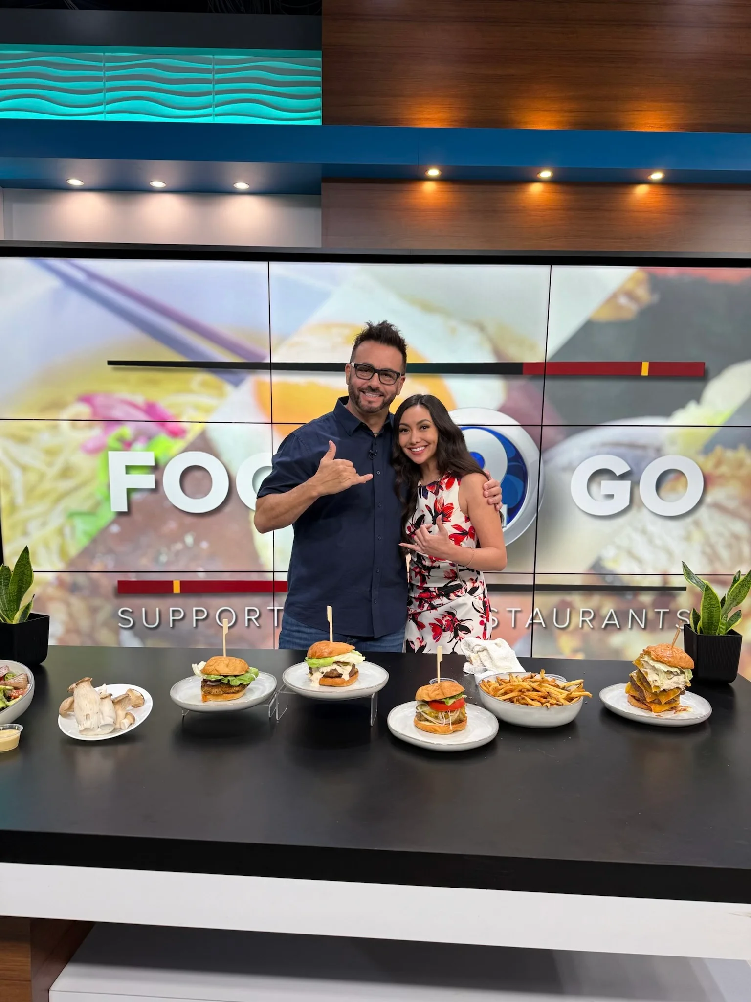 Chefs showcasing gourmet burgers on a television set