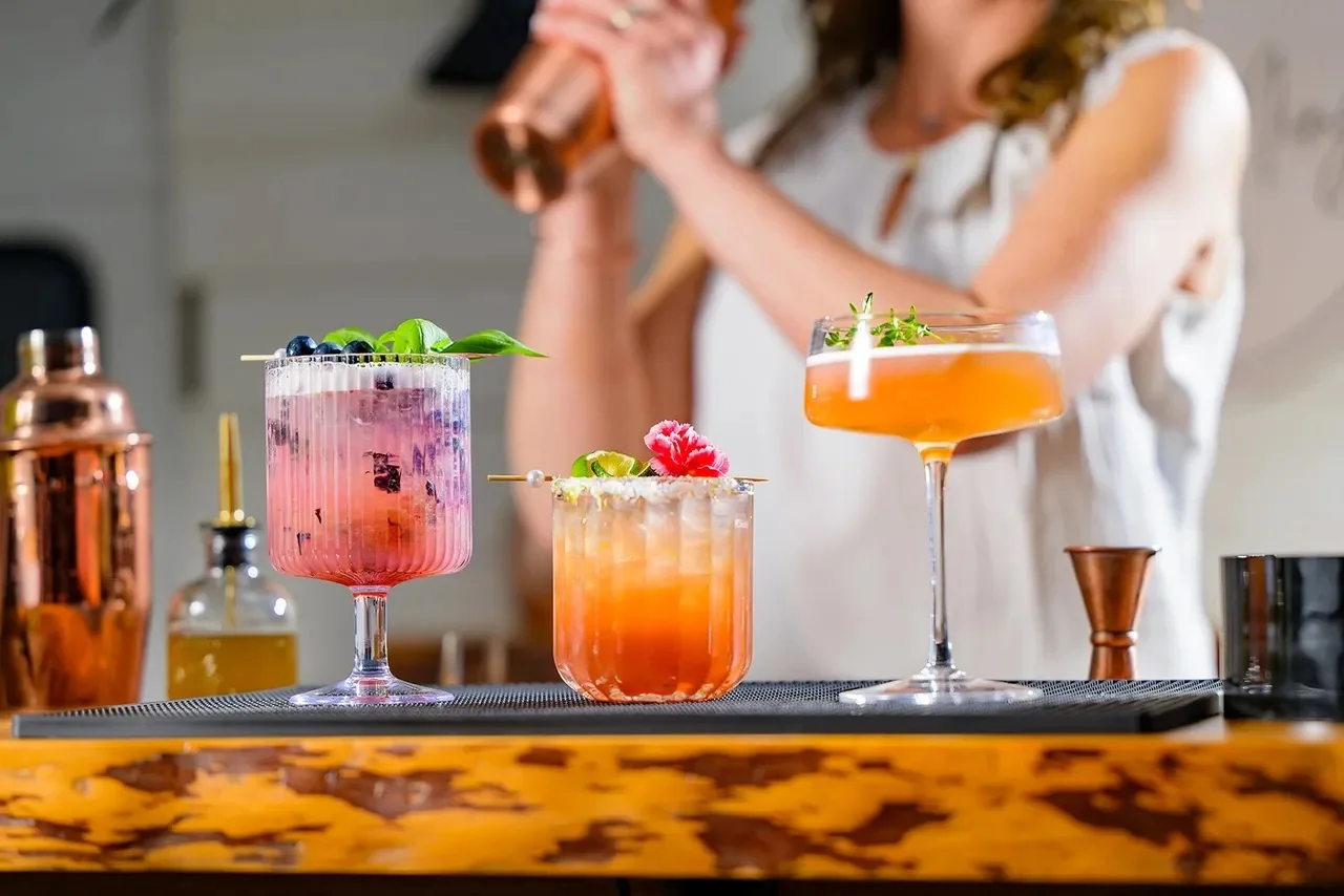 A vibrant display of colorful cocktails on a bar, featuring garnishes and decorative elements.