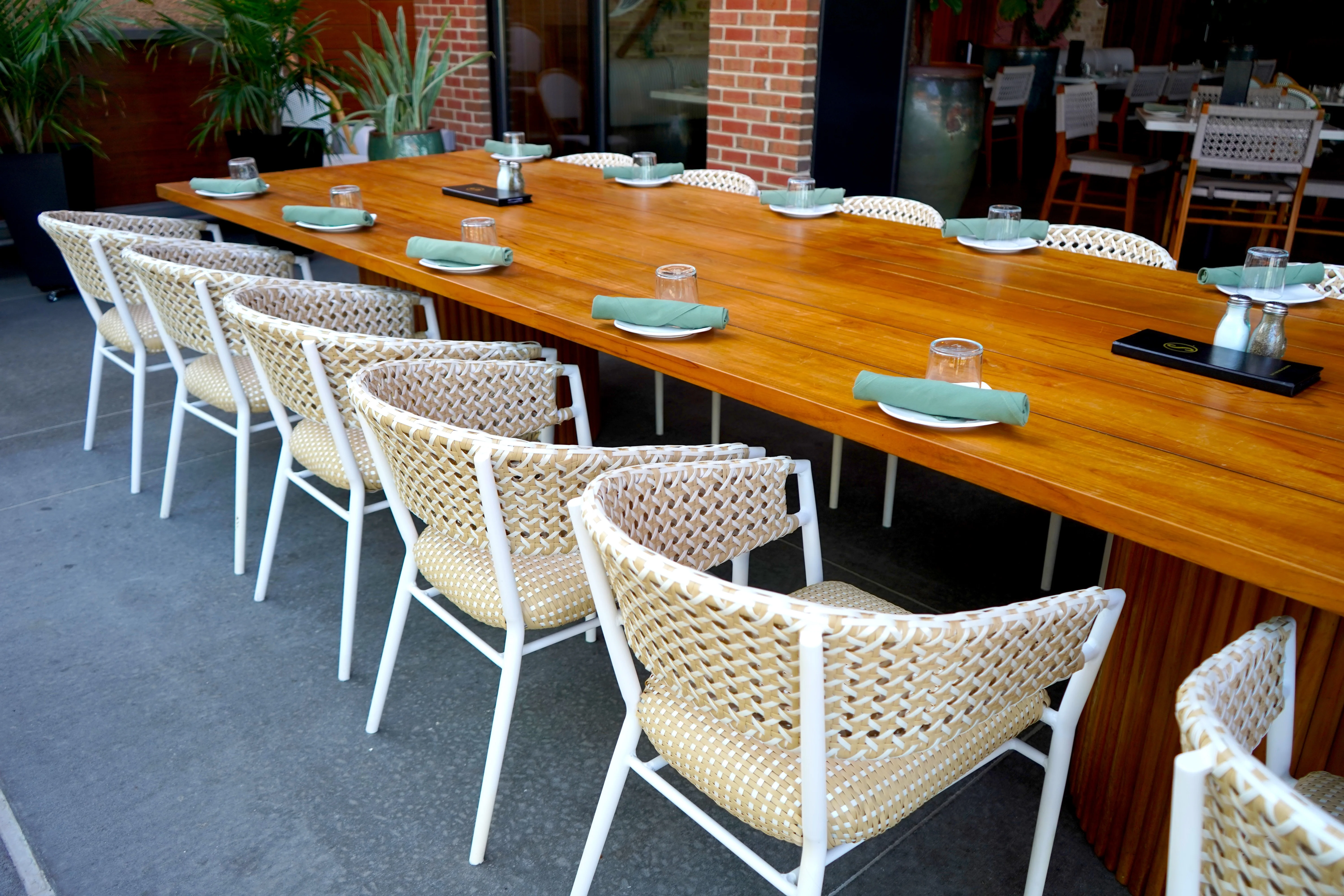 Stylish outdoor dining setup with woven chairs and wooden table