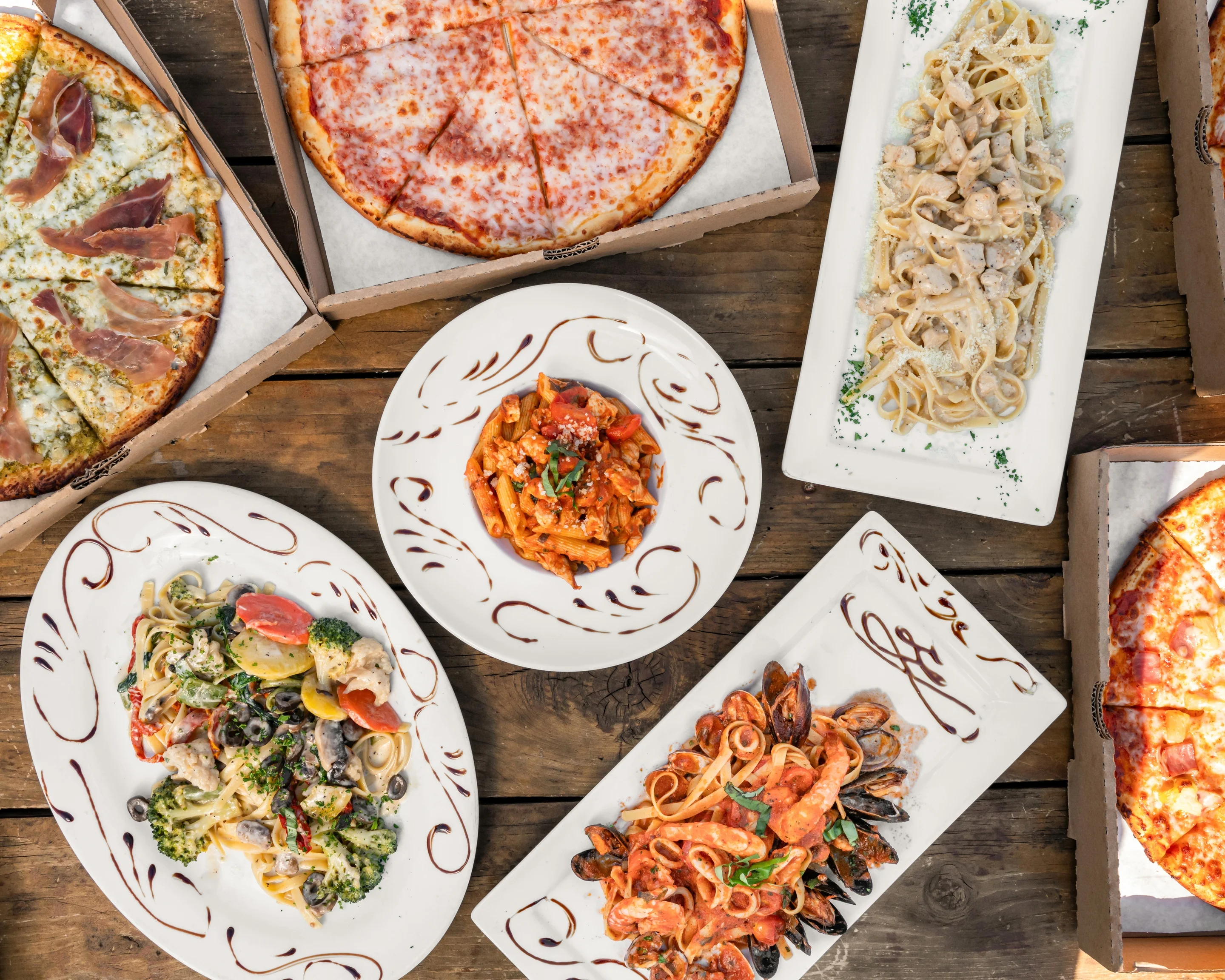 Italian pasta dishes and pizzas on a rustic wooden table