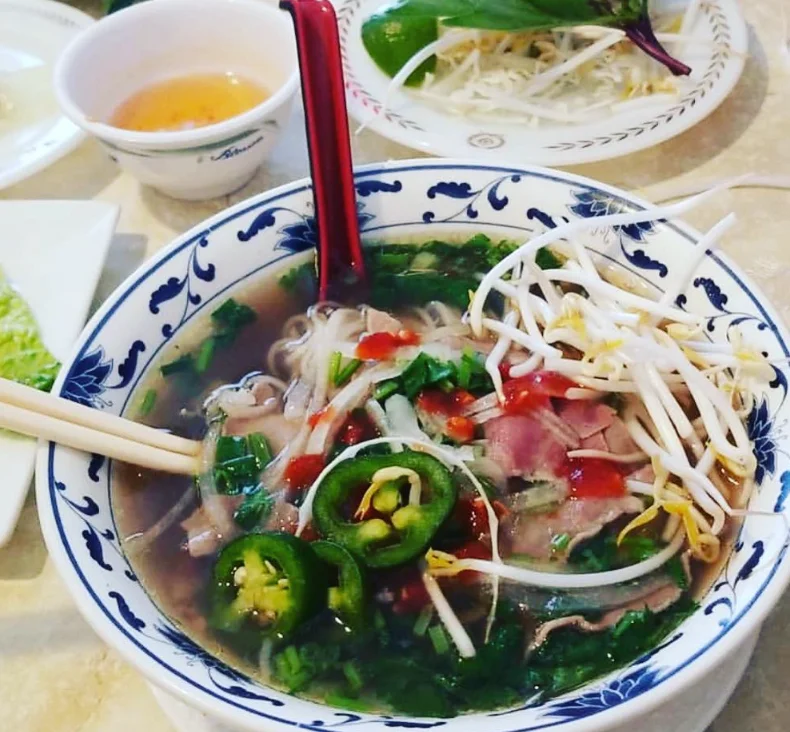 Bowl of Vietnamese pho with fresh herbs and lime