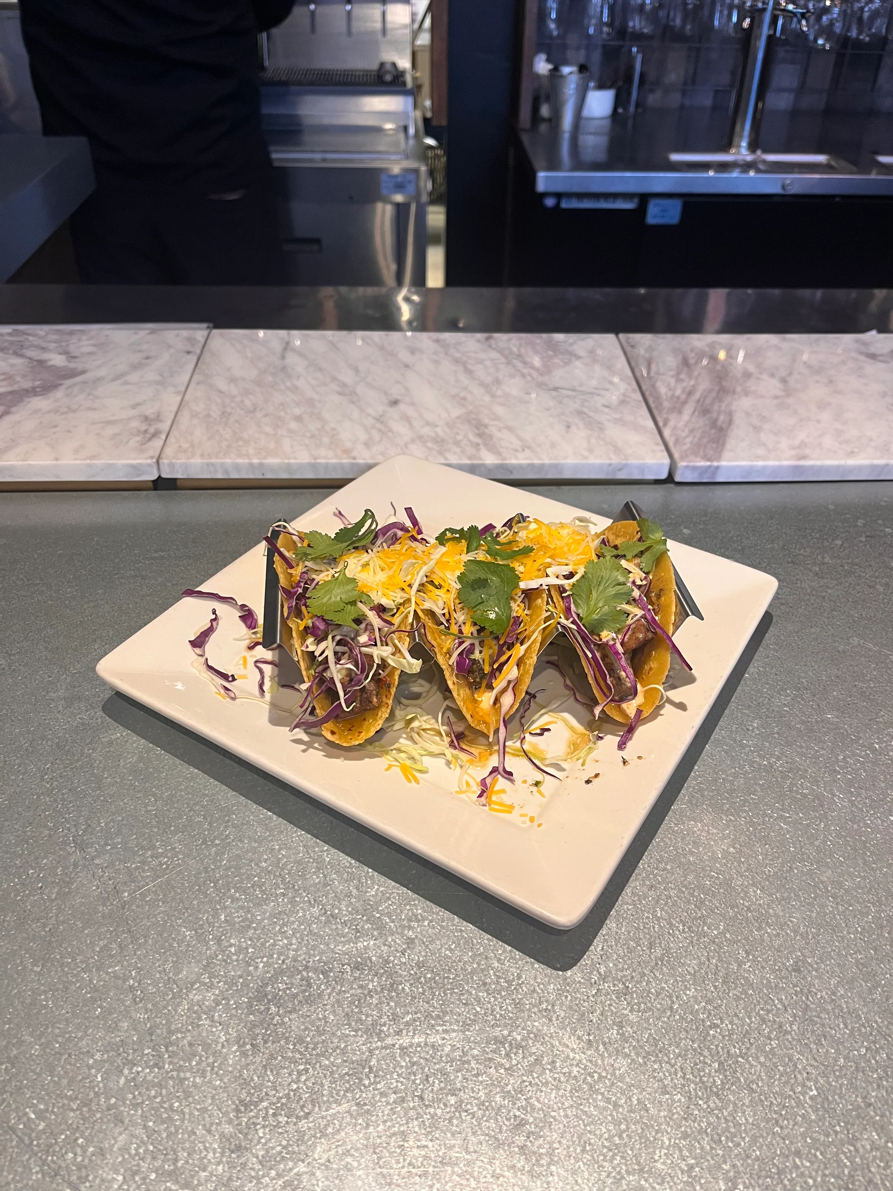 Three crispy tacos topped with fresh herbs