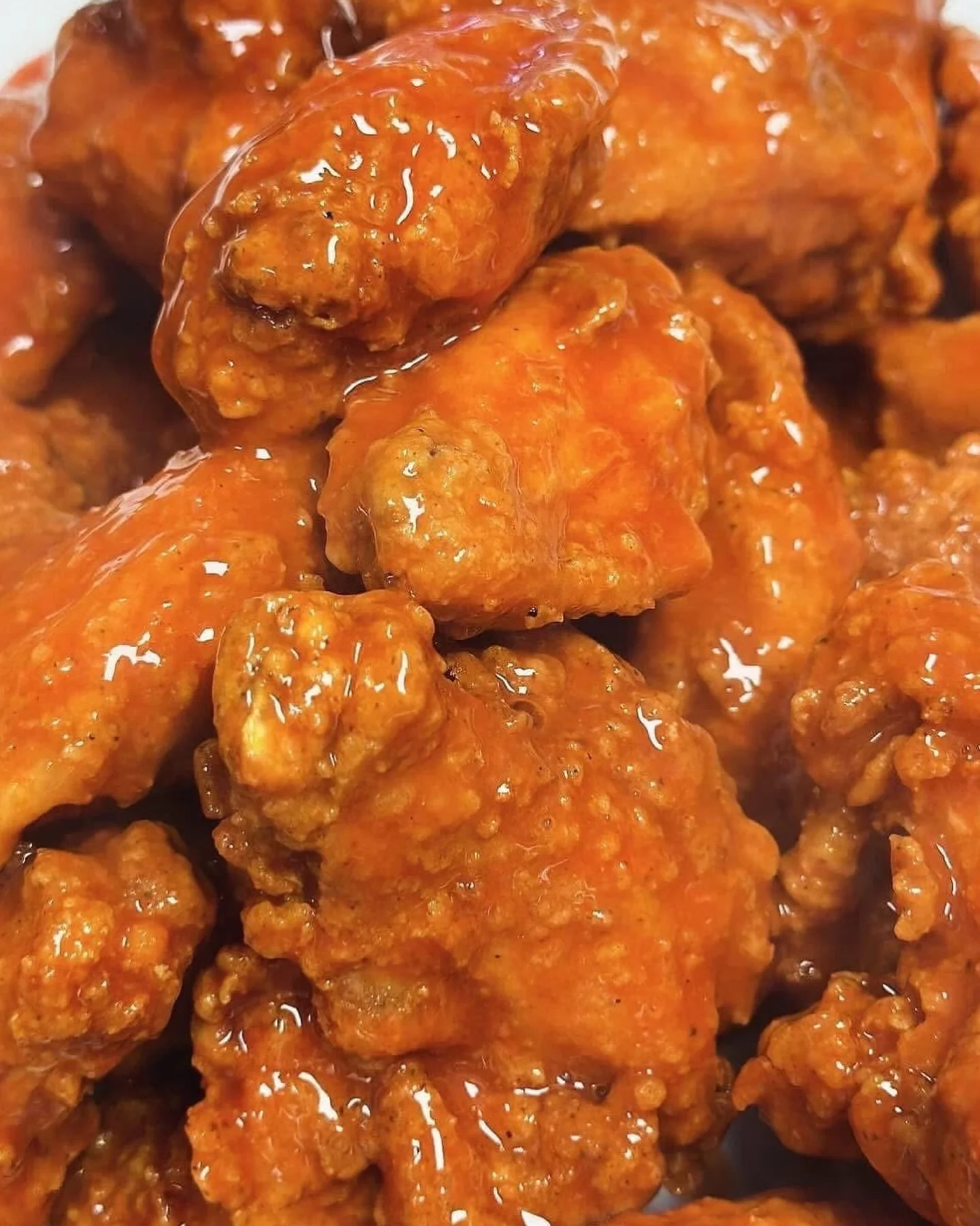 Close-up of glazed chicken wings in a rich orange sauce.