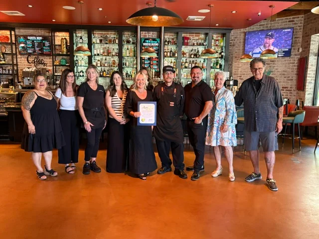 Team celebrating at a restaurant with award certificate