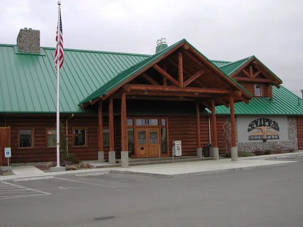 A decorative sign for a restaurant, featuring a longhorn skull and mountain graphics against a wood-paneled background.