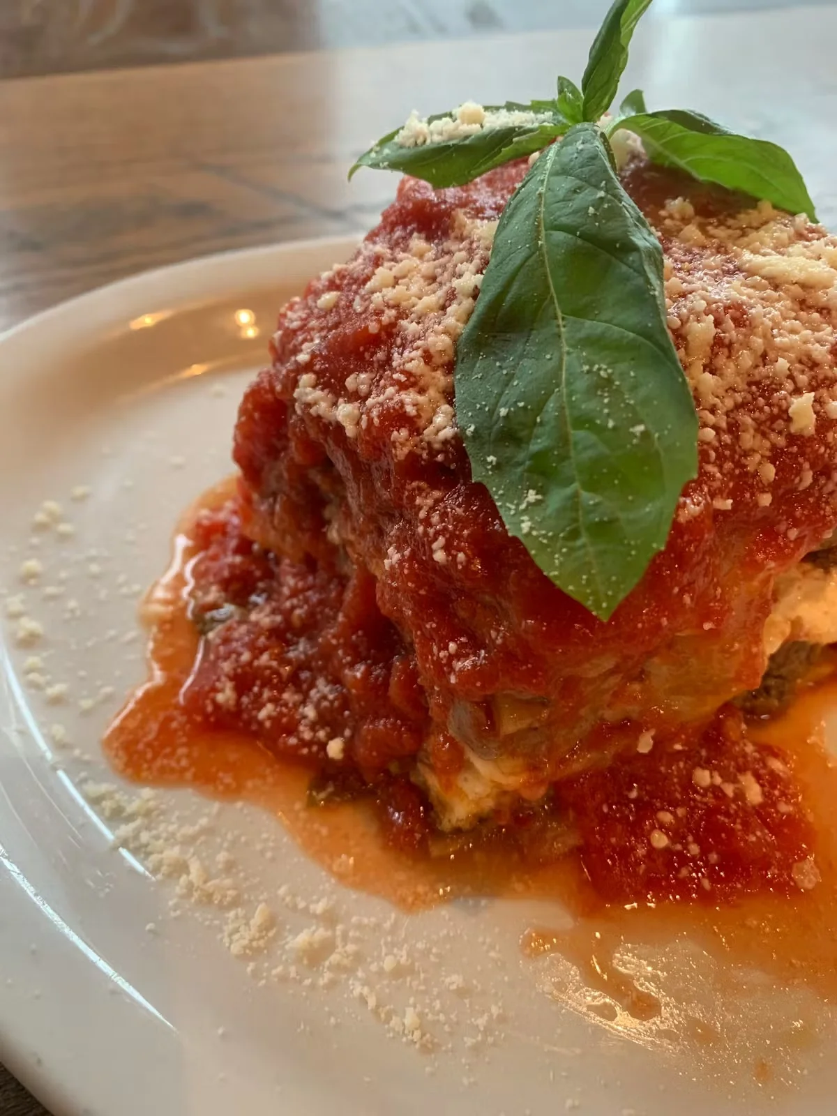 A serving of lasagna topped with tomato sauce and fresh basil.