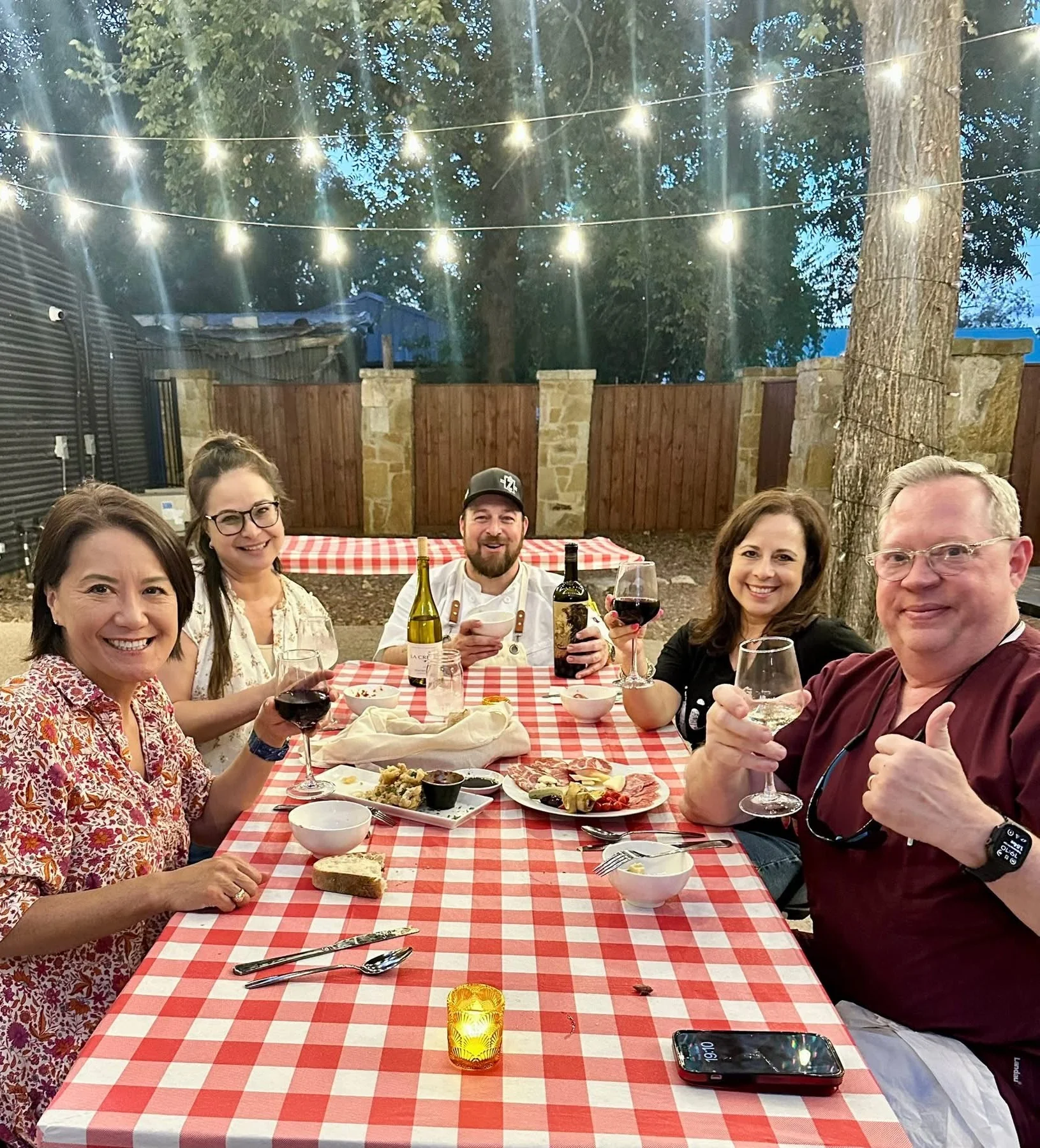 Group enjoying wine and appetizers at a cozy outdoor dining table