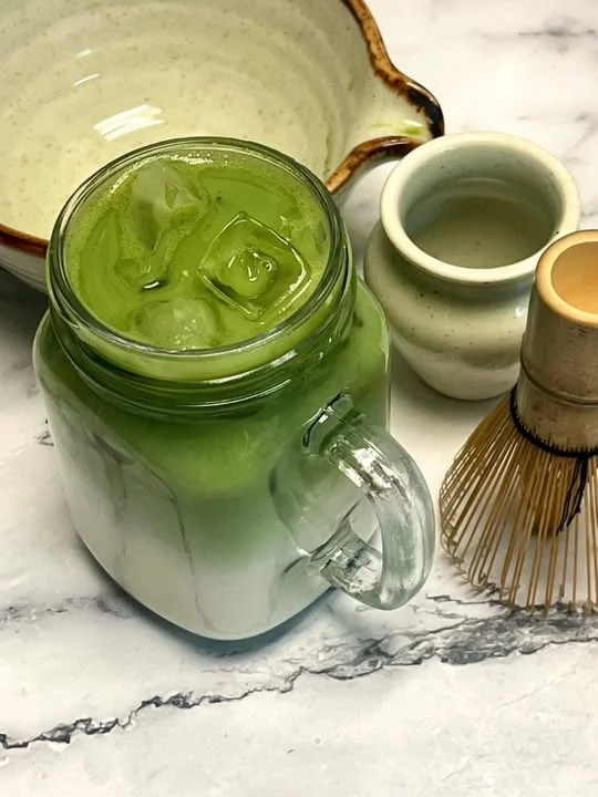 Iced matcha latte in a glass jar with milk
