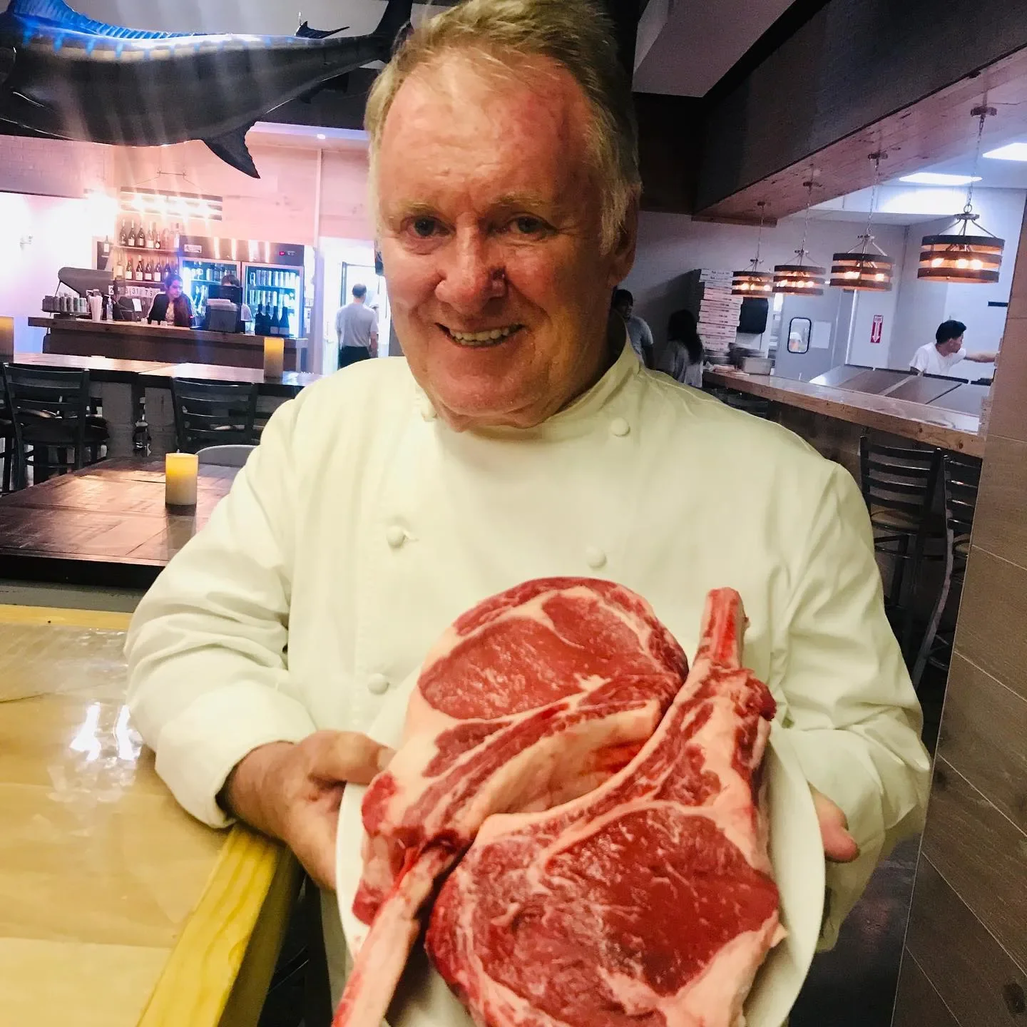 Chef presenting premium tomahawk steaks in a restaurant