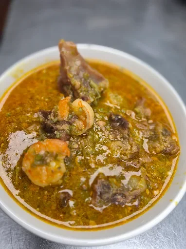 Nigerian egusi soup with shrimp and meat in a white bowl
