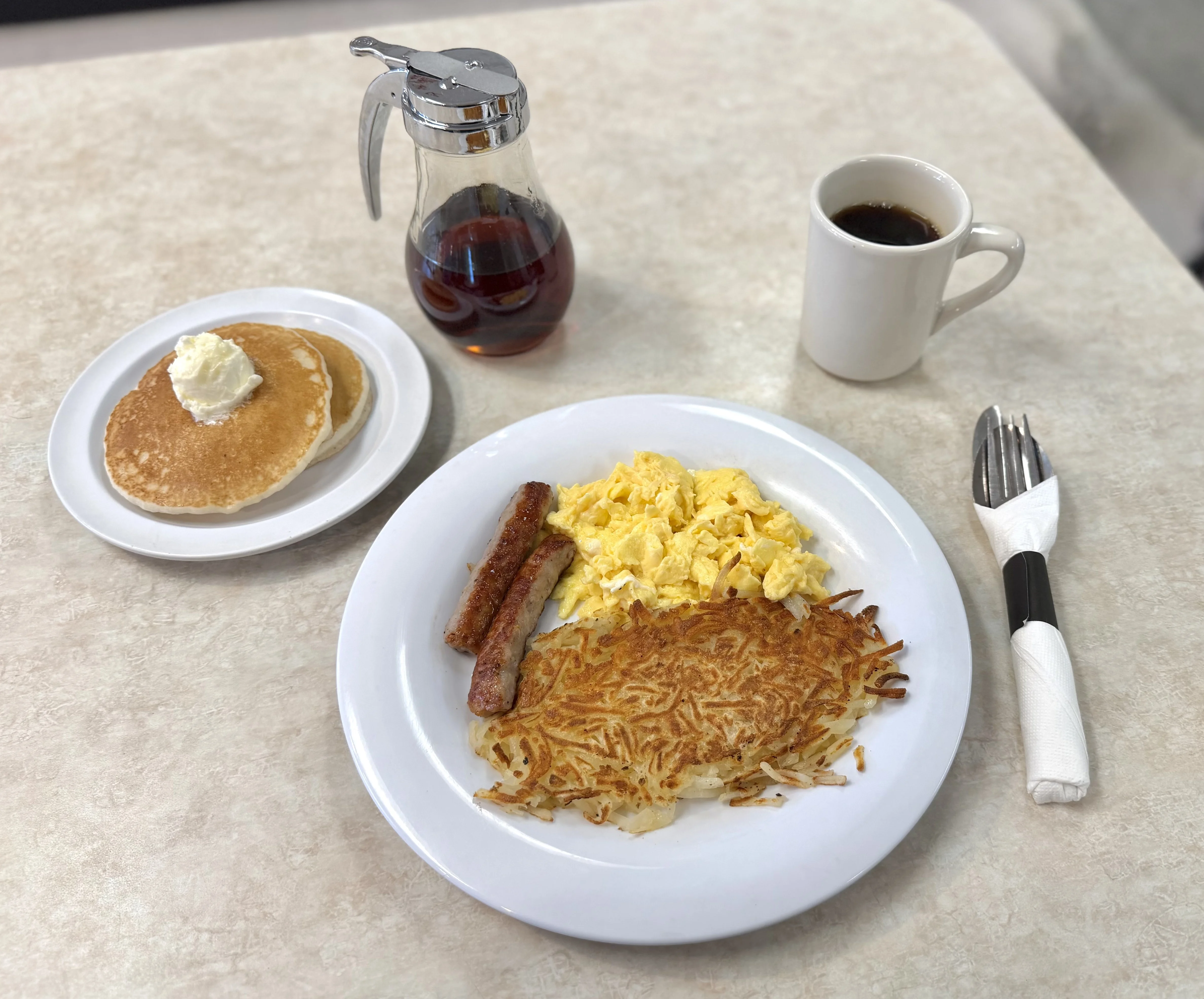 Classic American breakfast with pancakes, eggs, sausage, and coffee