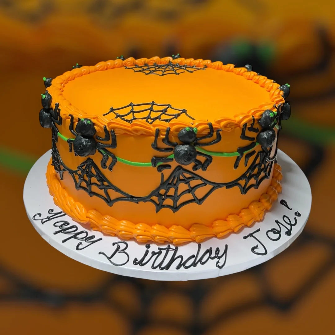 Halloween-themed birthday cake with orange frosting and spider decorations