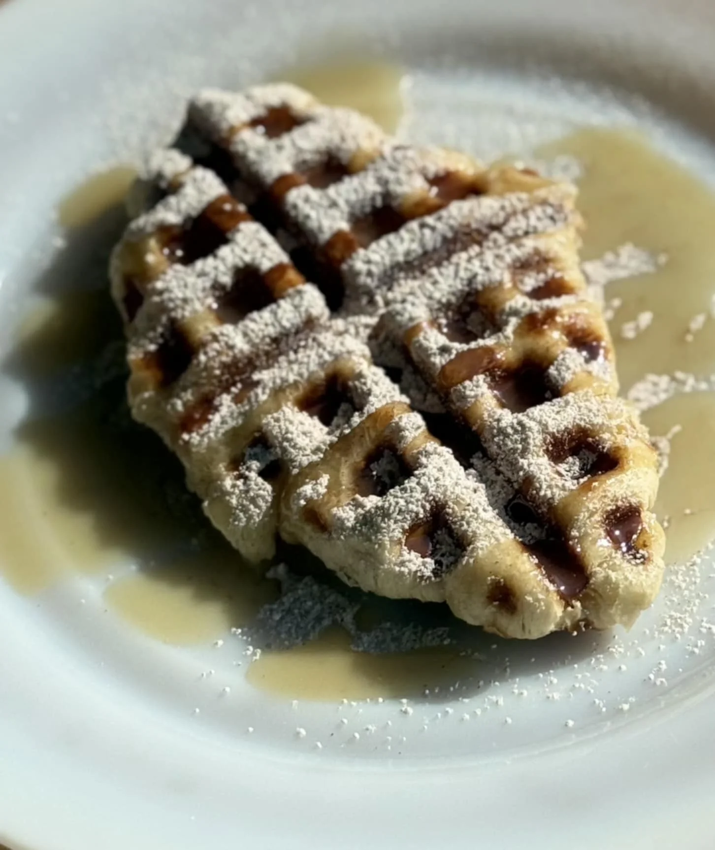 Belgian waffle dusted with powdered sugar and syrup