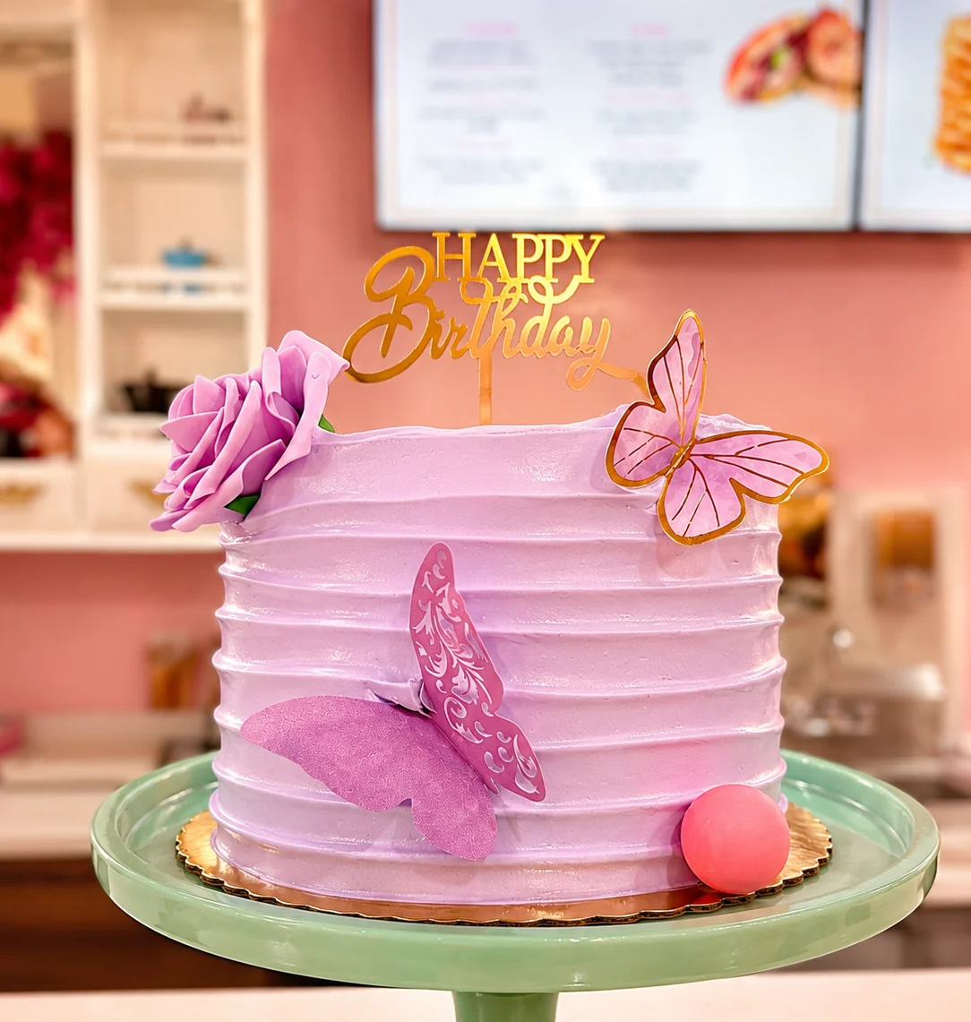 Elegant birthday cake with purple frosting and decorative butterflies