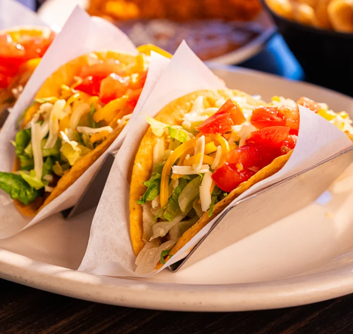Three delicious tacos served on a plate in a vibrant restaurant setting