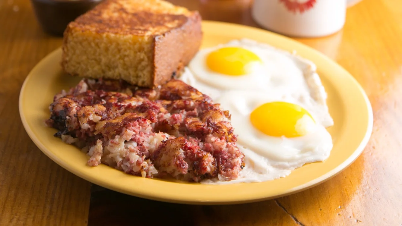 Classic American breakfast with eggs, corned beef hash, and cornbread