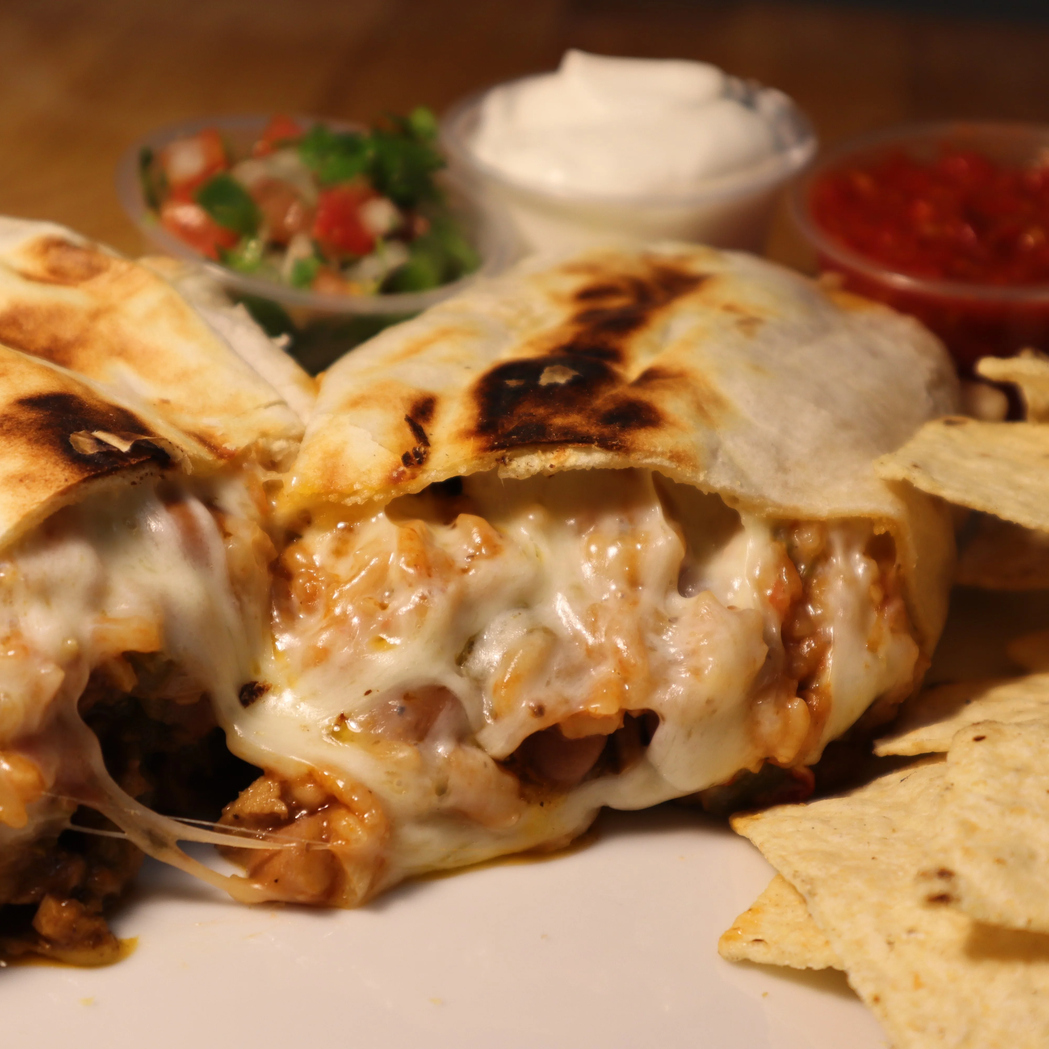 Cheesy chicken burrito with sides of salsa and guacamole