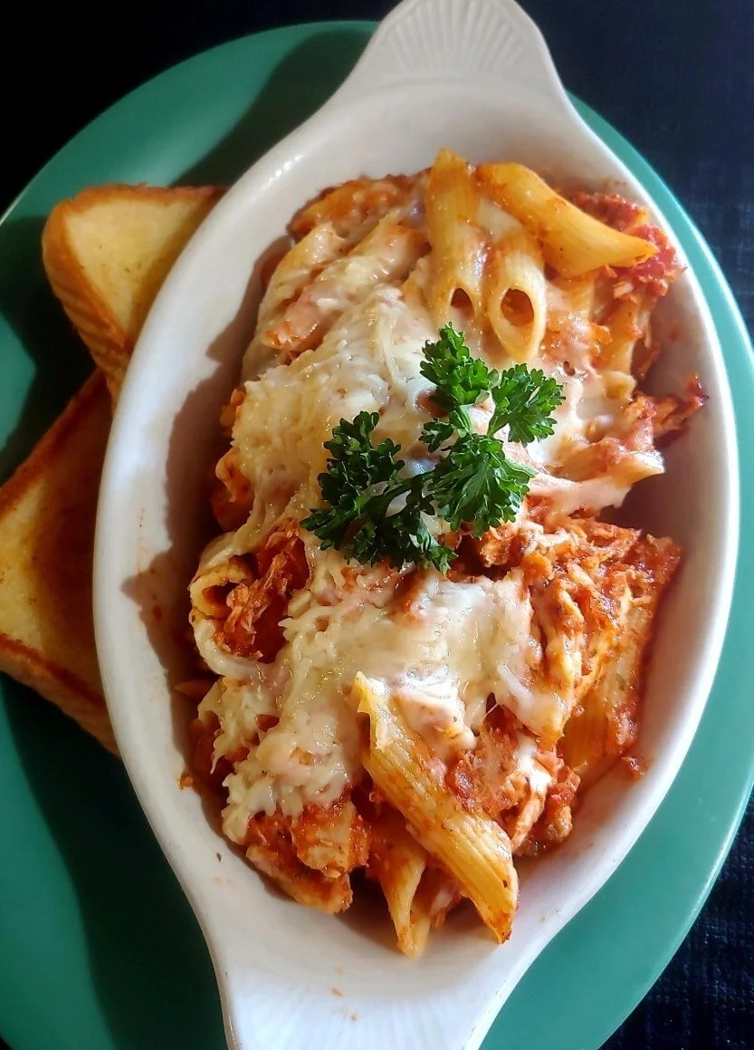 Baked ziti with melted cheese and garlic bread on the side