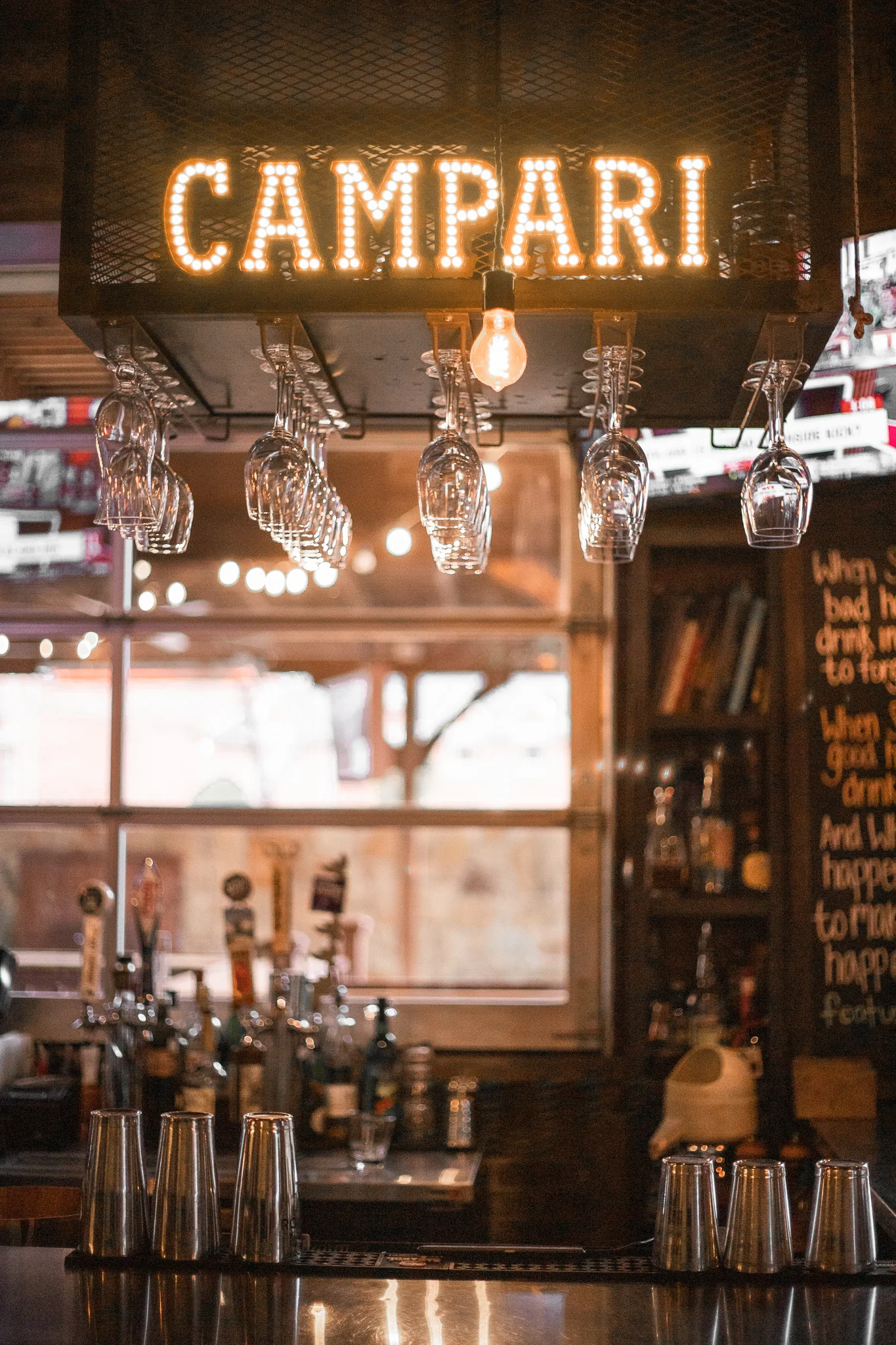 Cozy bar interior with Campari sign and hanging glasses