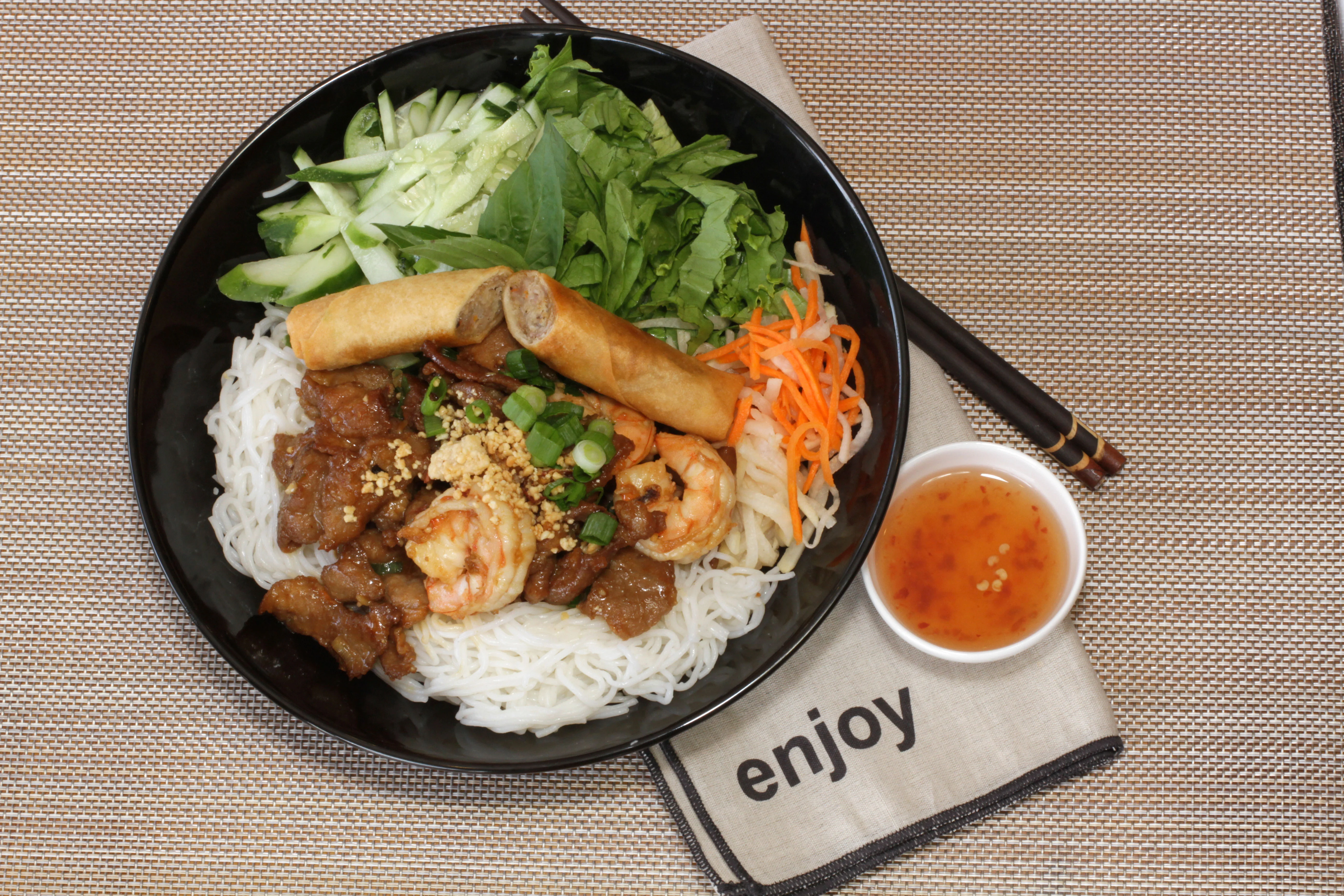 Vietnamese bun thit nuong with spring rolls and fresh herbs