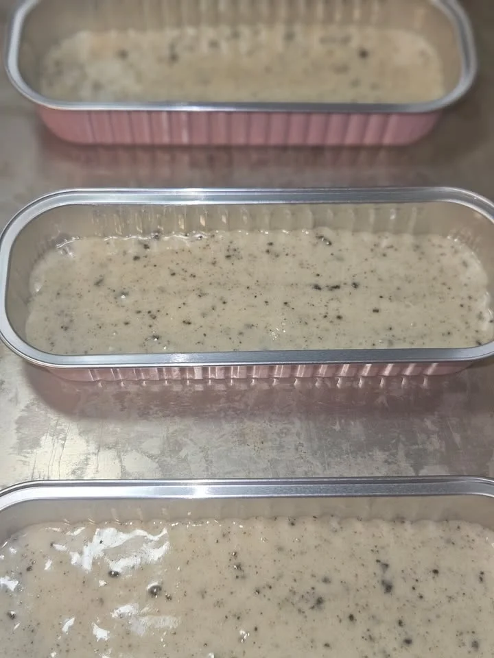 Three loaf pans filled with a light-colored batter studded with dark flecks, ready for baking.