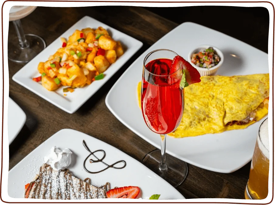 Colorful brunch spread featuring an omelette, cocktails, and dessert