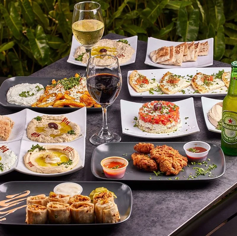Al fresco dining table with Mediterranean dishes and wine at Sufrat Grill.