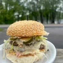 A juicy hamburger with lettuce, pickles, and sauce, served on a sesame seed bun.