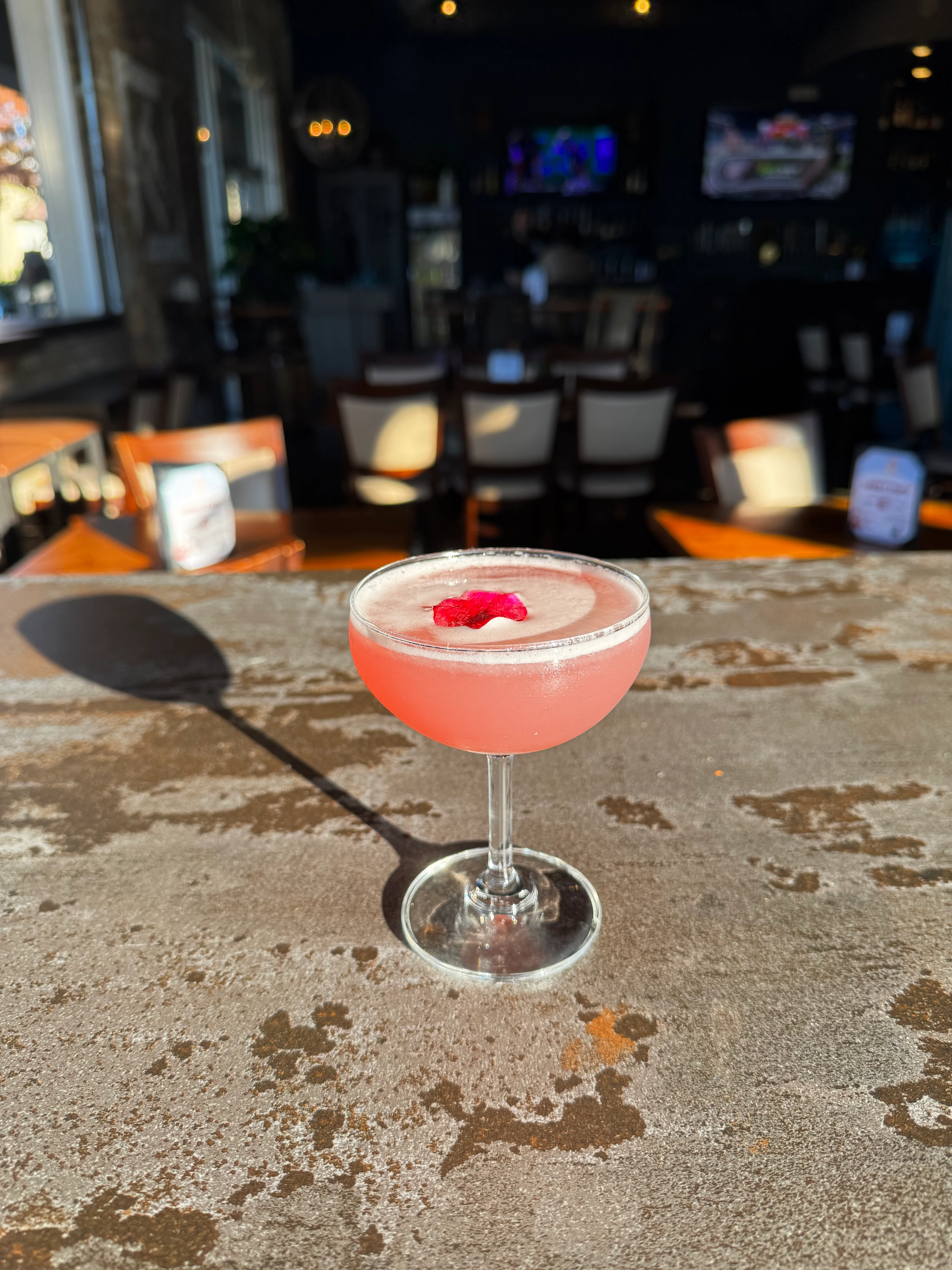 Refreshing pink cocktail garnished with a rose petal