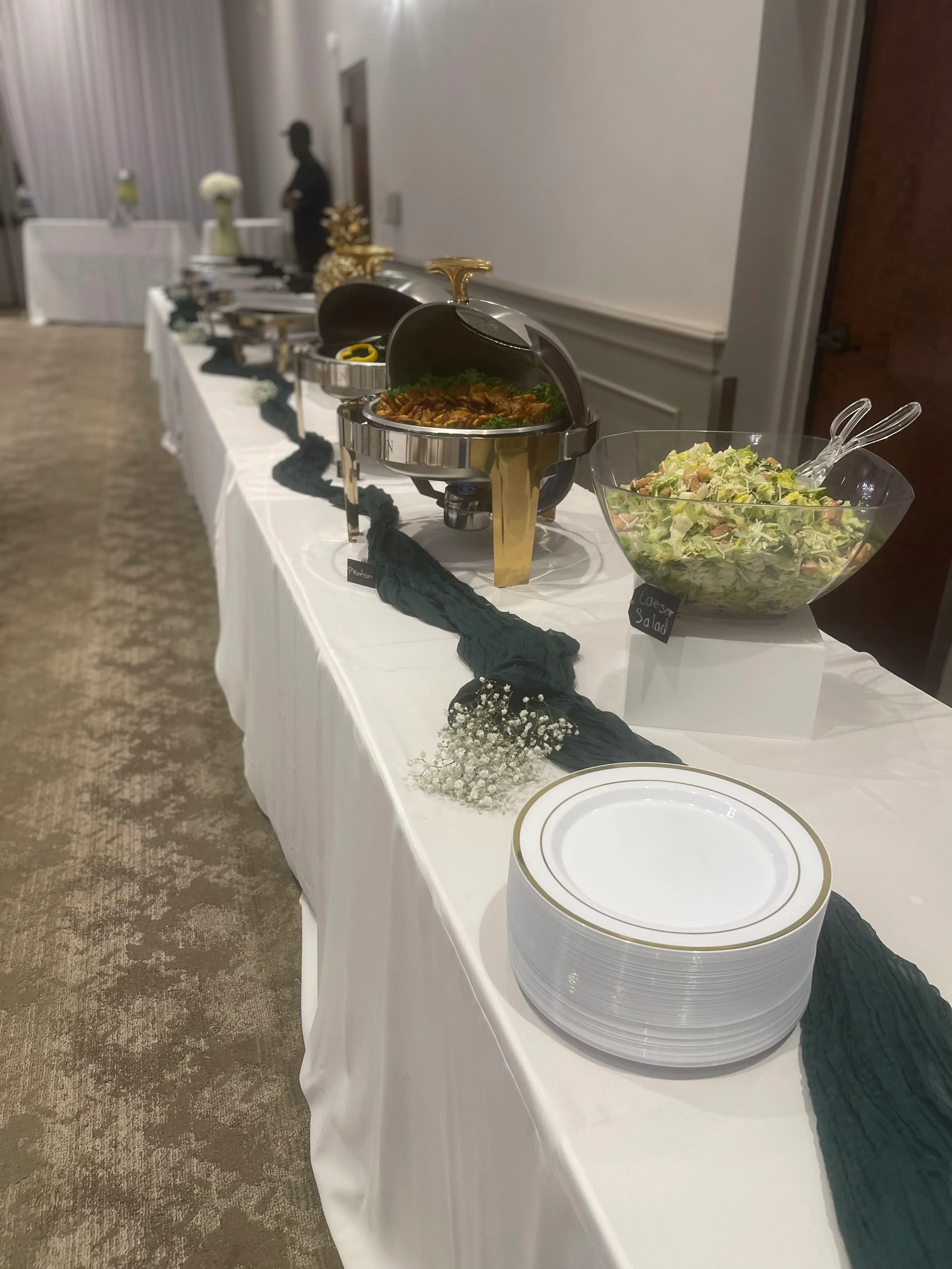 A buffet table setup with a variety of dishes, including salads and entrees, adorned with decorative elements and plates ready for serving.