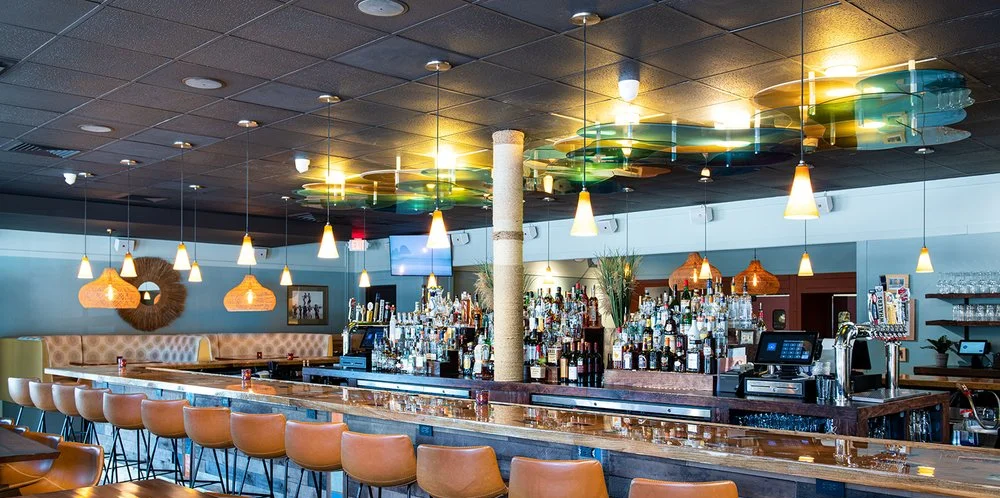 Modern restaurant bar interior with warm pendant lighting and leather bar stools