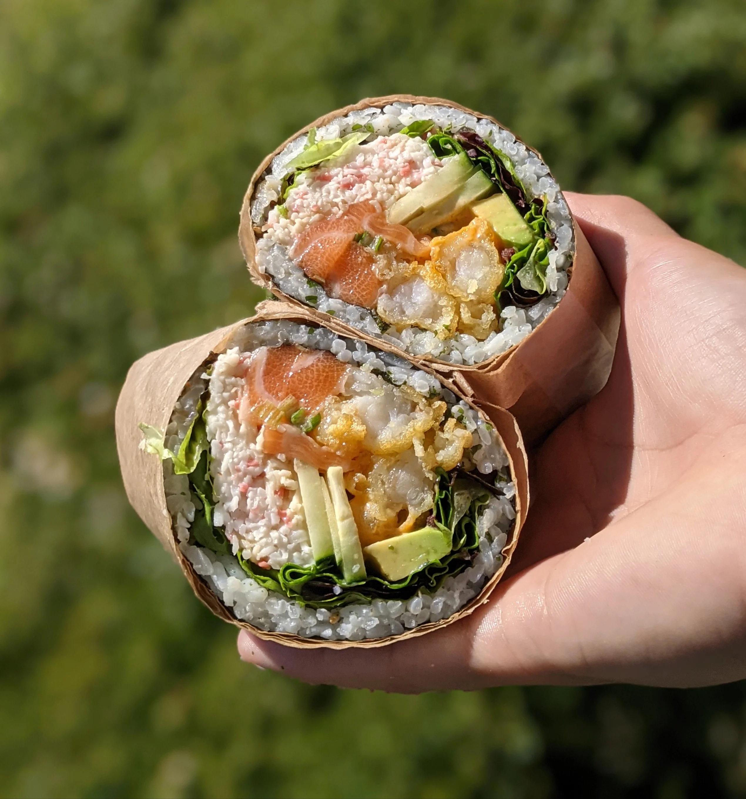 Two slices of sushi wrapped in nori with rice and a filling, neatly arranged on a white plate.