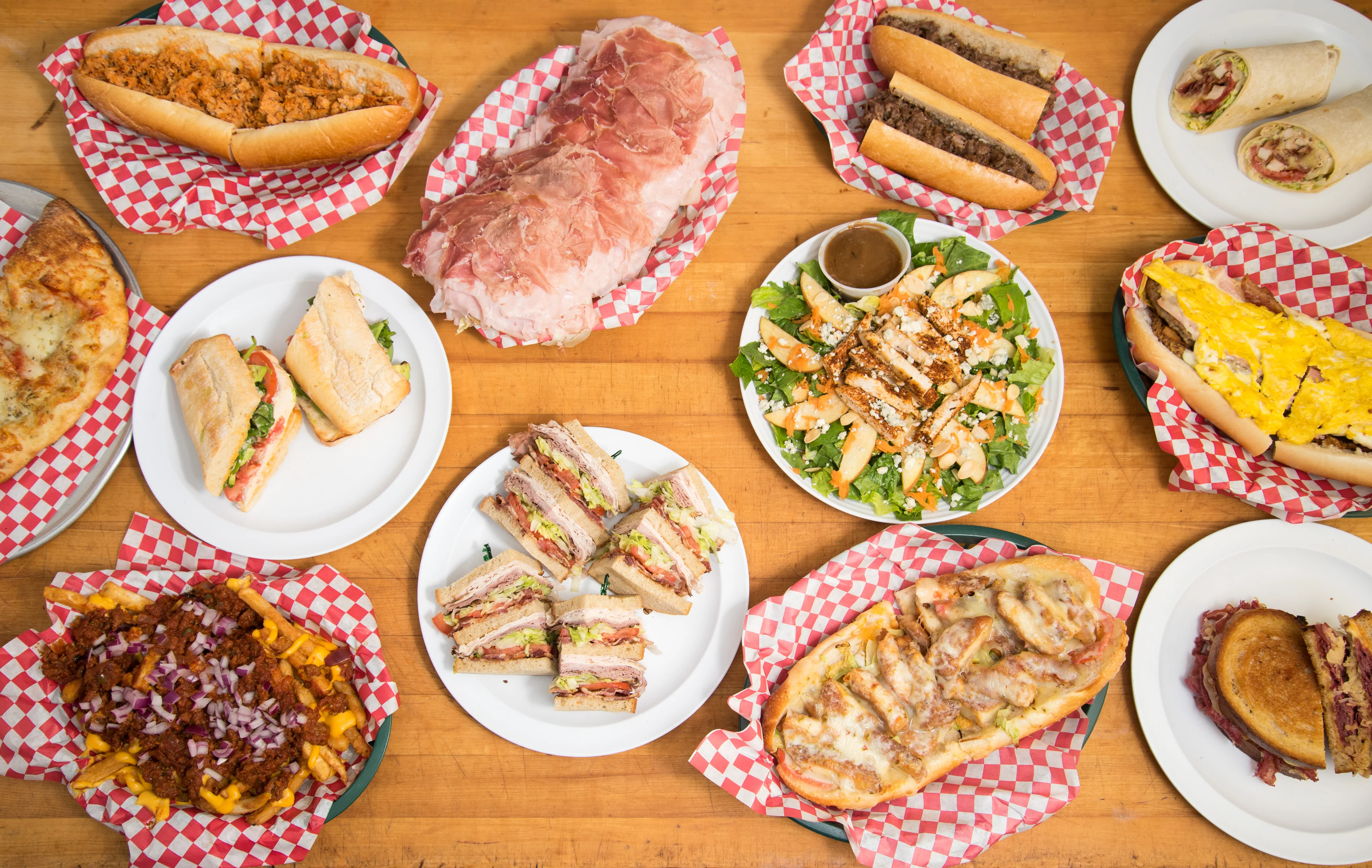 Assorted deli sandwiches and salads on a wooden table