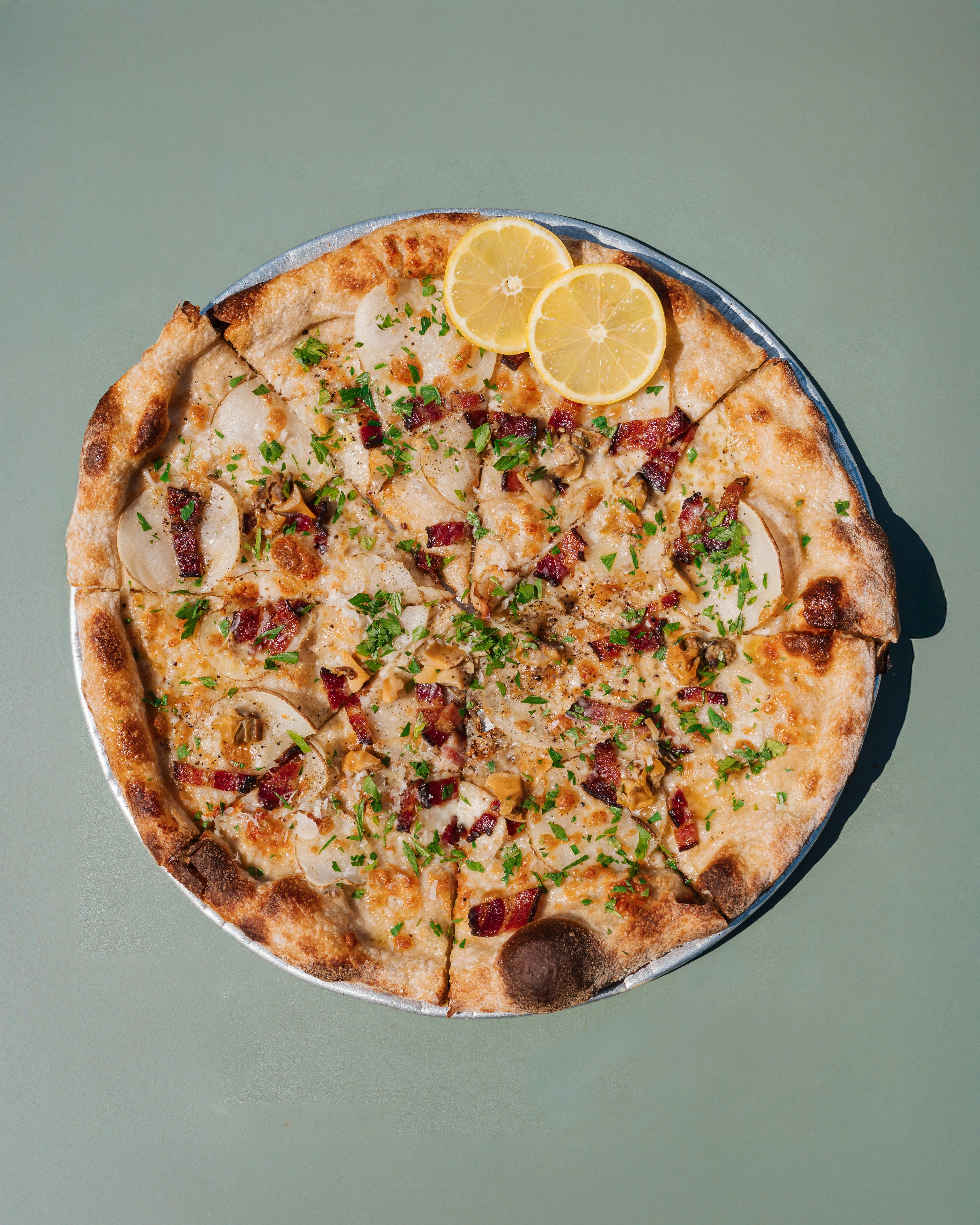 Gourmet pizza topped with bacon and lemon slices