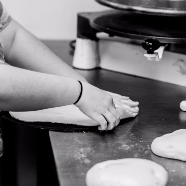 Chef shaping pizza dough on a wooden countertop