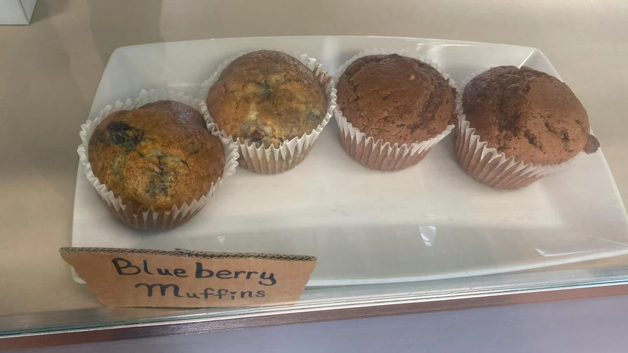 A selection of blueberry muffins displayed on a rectangular white plate. The muffins have golden-brown tops and paper liners.