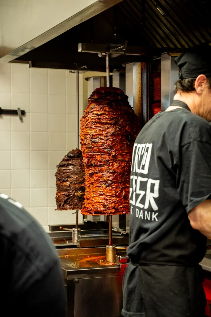 Vertical stack of marinated meat on a vertical rotisserie grill.