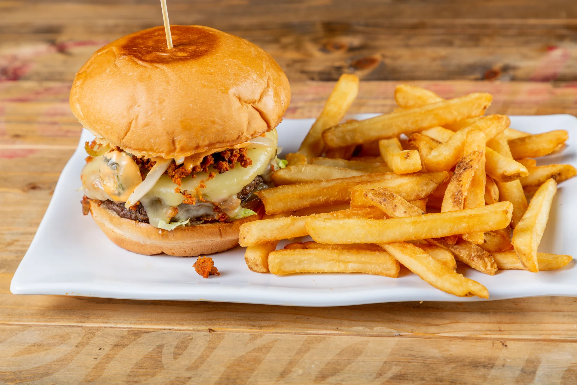 Juicy cheeseburger with fries on a white plate
