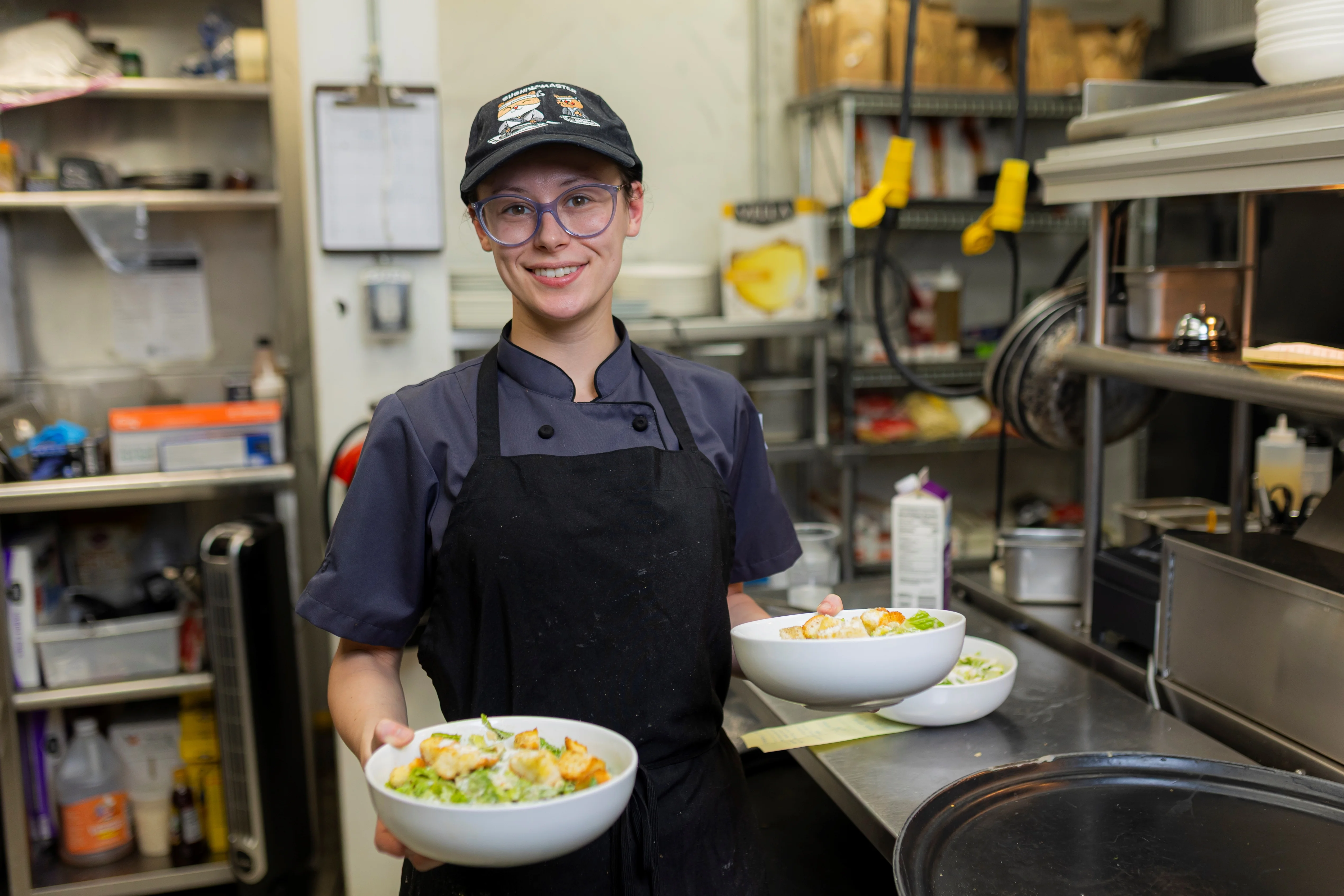 Chef presenting fresh Caesar salads in a bustling kitchen