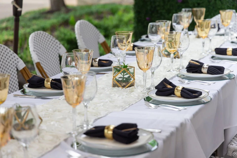 Elegant outdoor dining setup with gold accents and black napkins