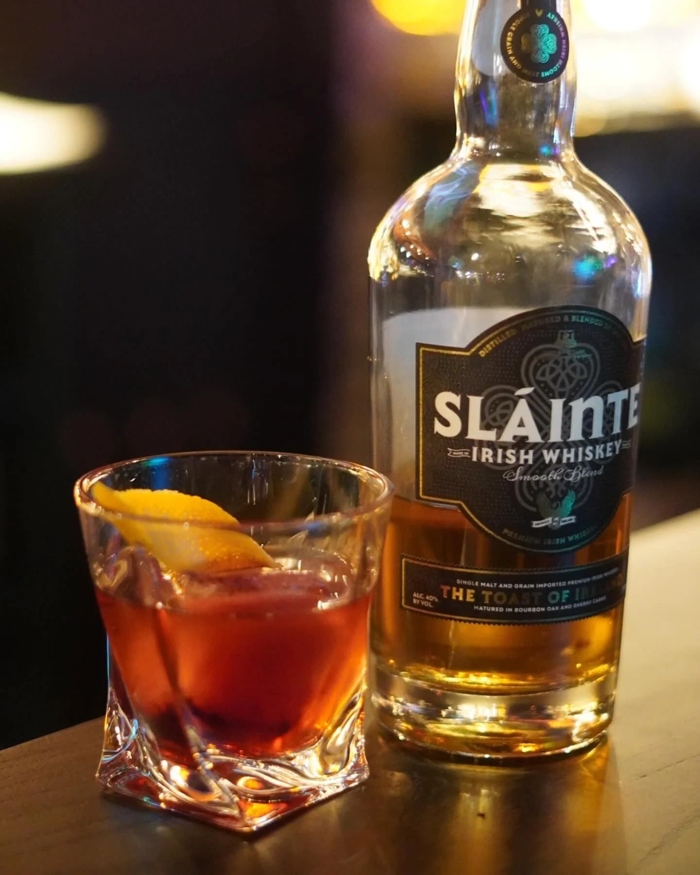 Glass of whiskey cocktail with lemon twist on a bar counter